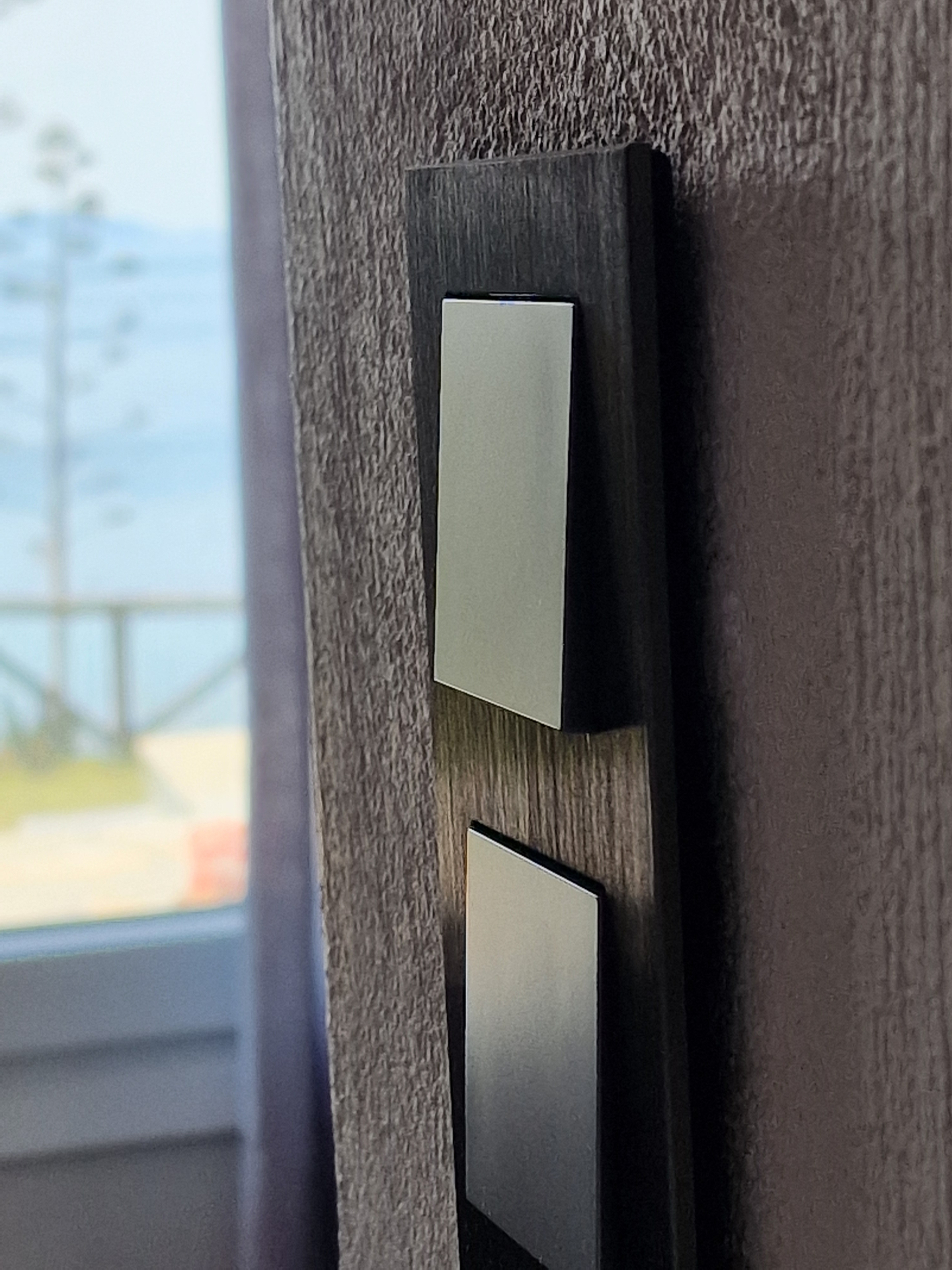Brushed light switch on the timber panel beside the sea view