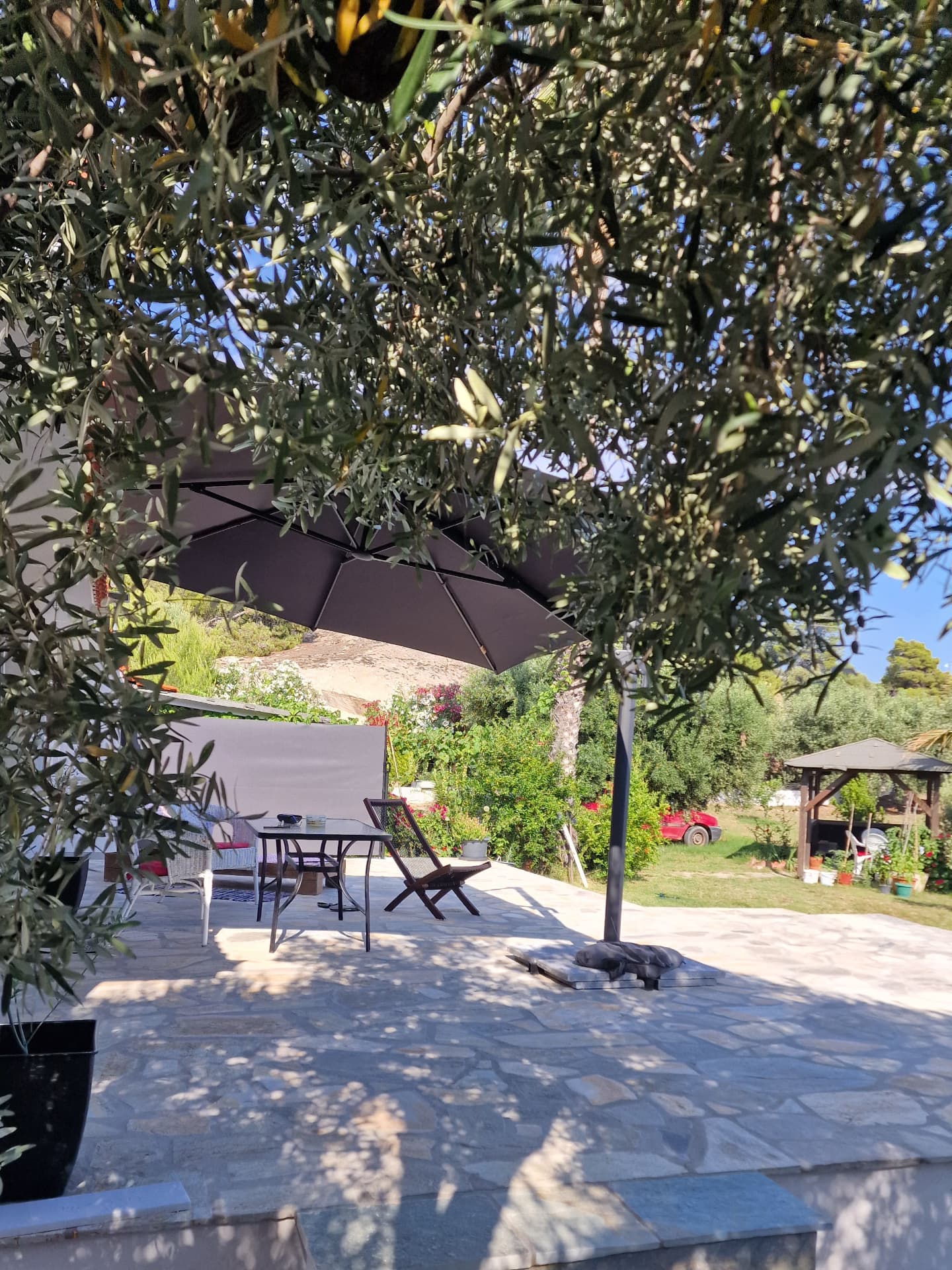 Shaded terrace dining area under a large parasol above the sea