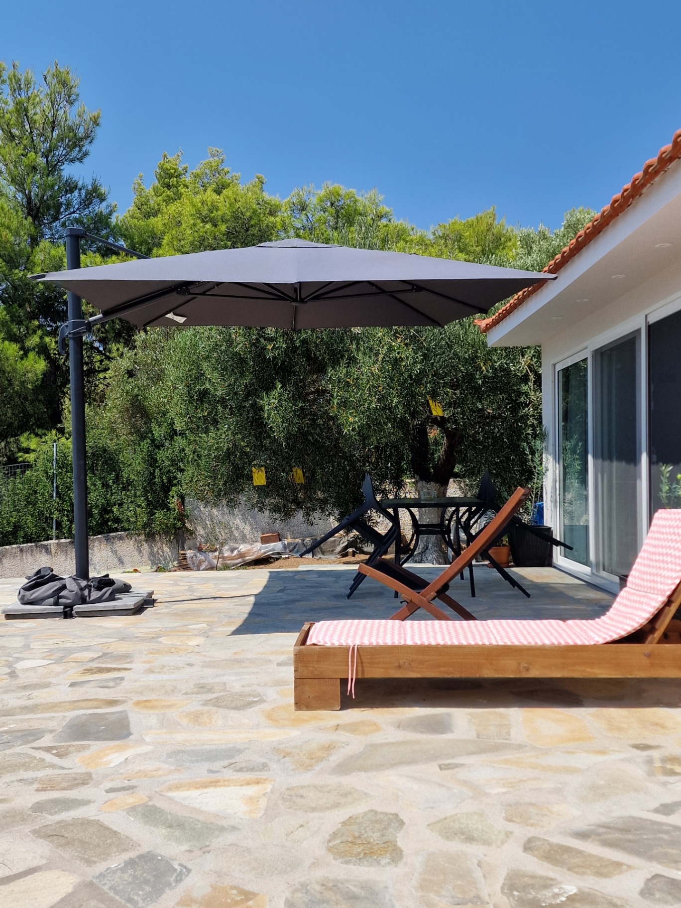 Parasol, loungers and pines on the stone terrace in Sithonia