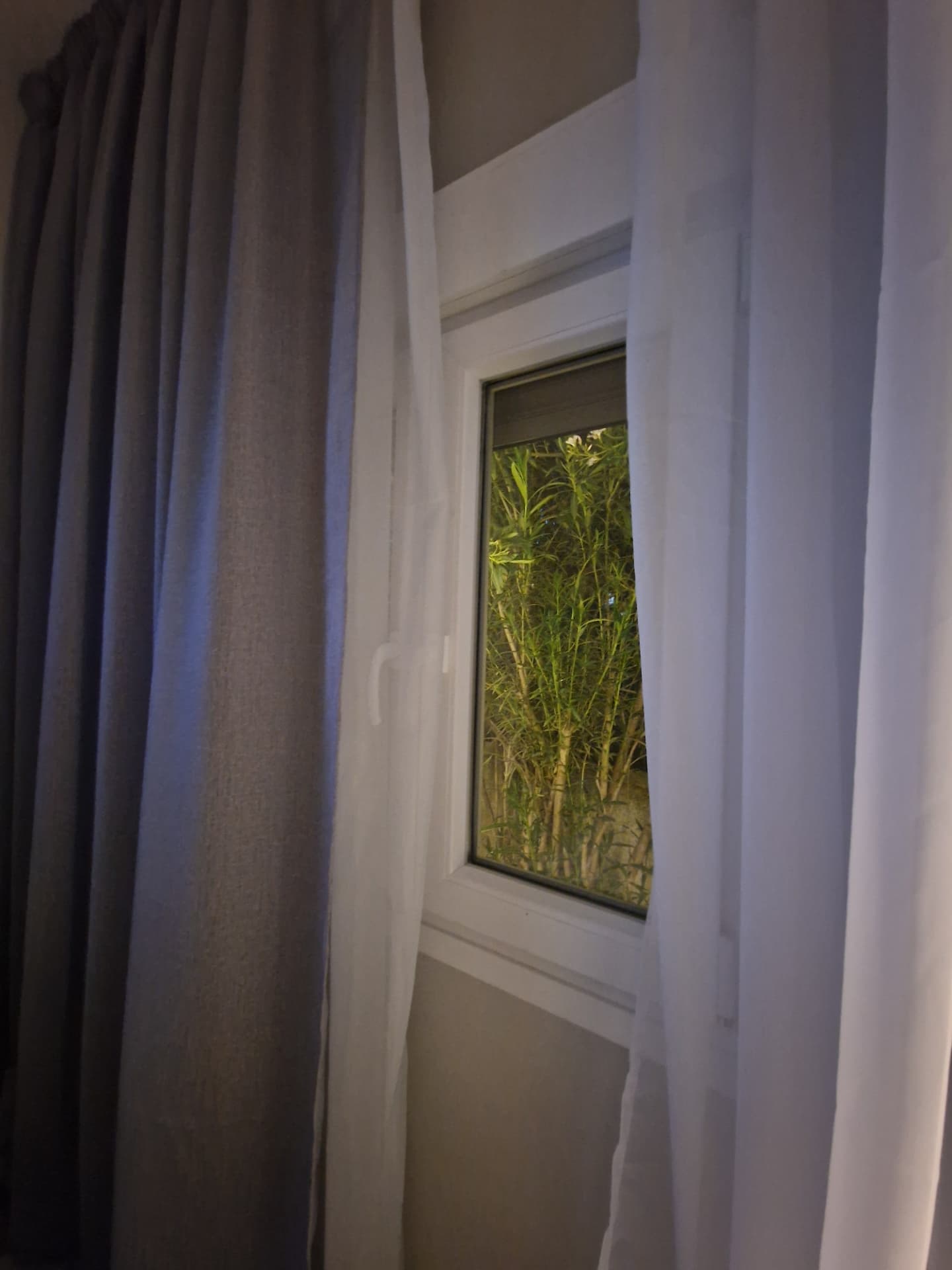 Sheer curtains framing the lit garden at night